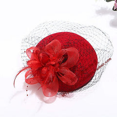 A red vintage-style fascinator hat featuring a decorative flower and black netting.