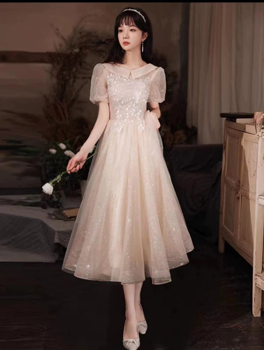 Elegant champagne embroidered evening gown by Showlu Fashion, featuring a mid-length design with intricate musical and art-inspired details.