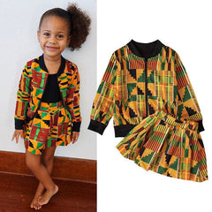 A young girl wears a patterned jacket and skirt set featuring a colorful geometric print.