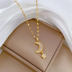 A gold-toned stainless steel necklace featuring a crescent moon and star pendant with clear stones.