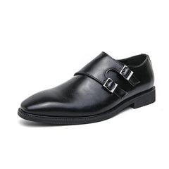 A pair of black leather monk strap dress shoes featuring a pointed toe and double silver buckles.