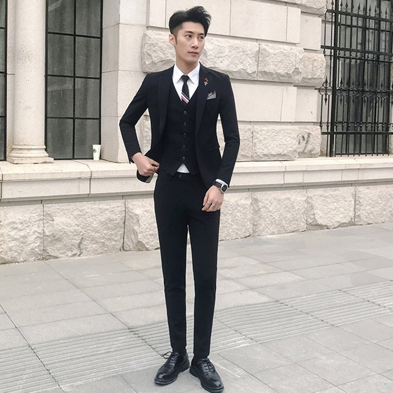 Slim-fit three-piece wedding suit for men, Korean style, showing a casual dark color with a tailored blazer, vest, and trousers.
