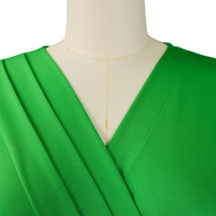 A close-up of a bright green V-neck dress with pleated detailing on a mannequin.