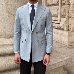 A man wears a light grey, double-breasted suit jacket with vertical stripes and gold buttons.