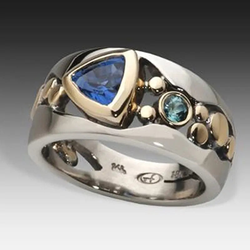 Elegant women's silver and gold hollow out ring with inlaid blue stone, perfect as a wedding or engagement jewelry piece.