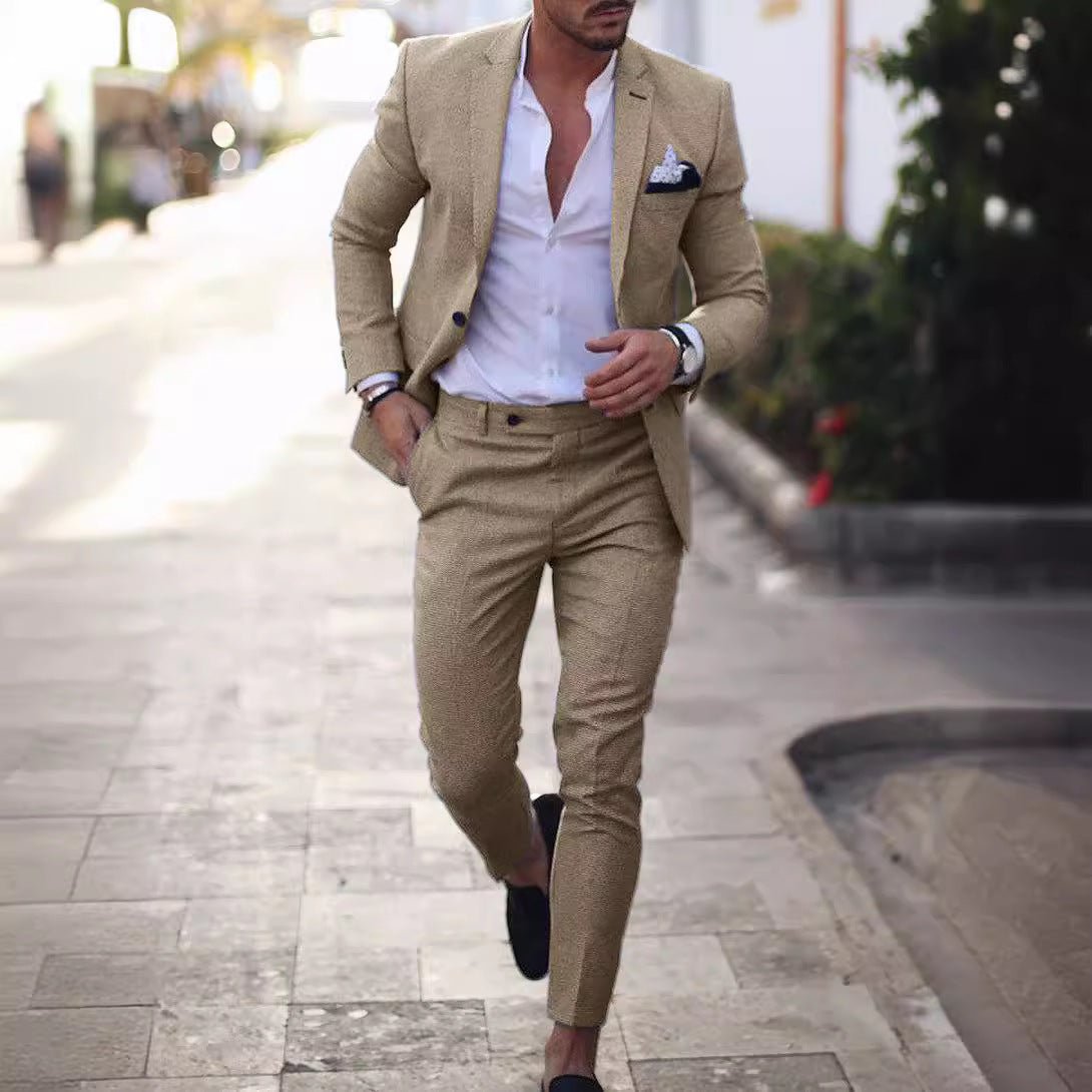 A man wears a slim-fit beige suit with a white button-down shirt and dark loafers.