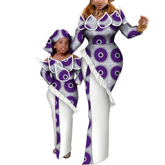 A mother and daughter wear matching purple and white African wax print maxi dresses.