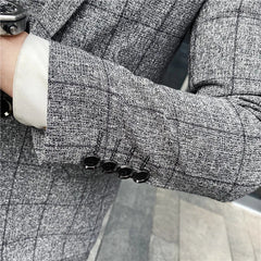 A close-up of a grey plaid suit sleeve featuring four black buttons at the cuff.