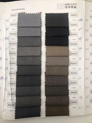 A fabric swatch book displaying various shades of grey, black, and brown suit materials.