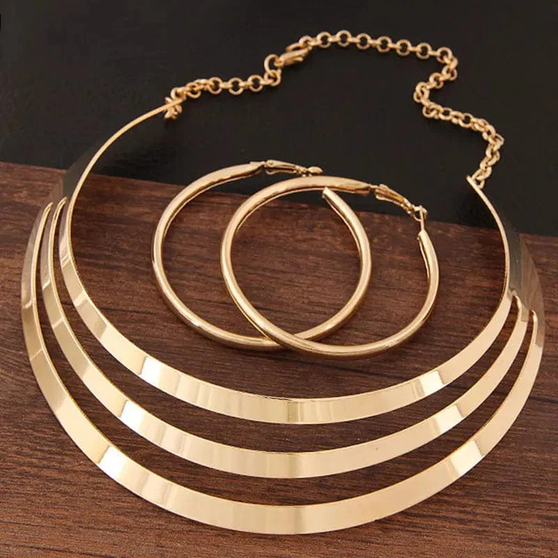Gold torques necklace and round earrings set by KMVEXO, stylish women's jewelry for parties and special occasions.