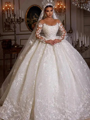 A long-sleeved ball gown wedding dress featuring sequined tulle, lace appliques, and a sheer neck.