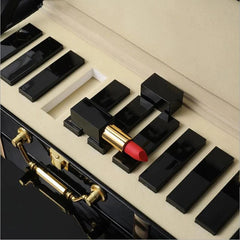 A set of black lipstick tubes arranged like piano keys in a gift box with one open red lipstick.