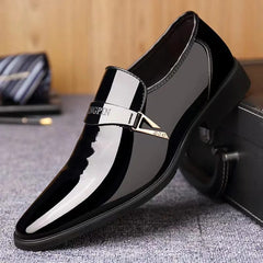 A black glossy slip-on loafer for men featuring a decorative metallic strap across the vamp.