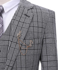 A grey plaid wool suit jacket with a musical note brooch and chain detail.