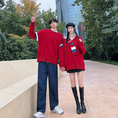 A couple wears matching red long-sleeved knit sweaters with blue and white striped accents.