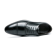 A black leather lace-up oxford shoe with decorative brogue detailing on the toe cap.