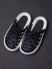 A pair of black closed-toe sandals with a woven upper and a thick white platform sole.