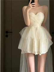 A cream-colored strapless mini dress with a lace bodice and a layered tulle tutu skirt.