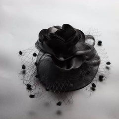 A black fascinator hair clip featuring a satin rose and a dotted mesh veil.
