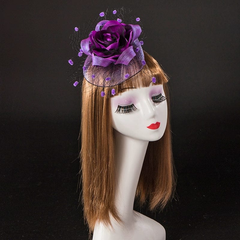 A mannequin head wears a purple rose fascinator with a netted veil and small purple accents.
