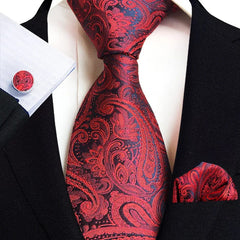 A red and black paisley patterned necktie, pocket square, and matching cufflink set.