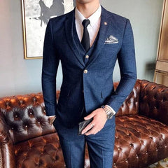 A man wears a navy blue plaid three-piece suit with a white shirt and black tie.