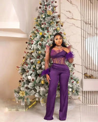 A woman wears a purple long-sleeved jumpsuit with feather cuffs and a sheer beaded bodice.