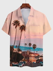 A short-sleeved button-down shirt featuring a scenic coastal sunset print with palm trees.
