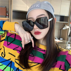 A woman wears oversized square polarized sunglasses with black frames and dark lenses.