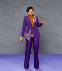A woman wears a tailored purple two-piece suit featuring crystal embellishments and gold embroidery.
