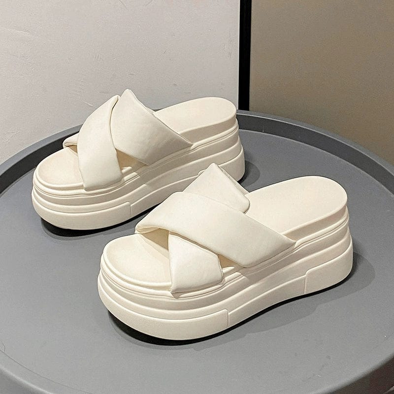 A pair of white platform slide sandals with thick crisscross straps on a chunky muffin heel.