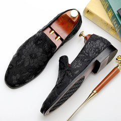 A pair of black slip-on loafers featuring an intricate floral embroidered pattern.