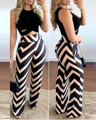A woman wears a sleeveless black cropped top paired with high-waisted chevron-patterned trousers.