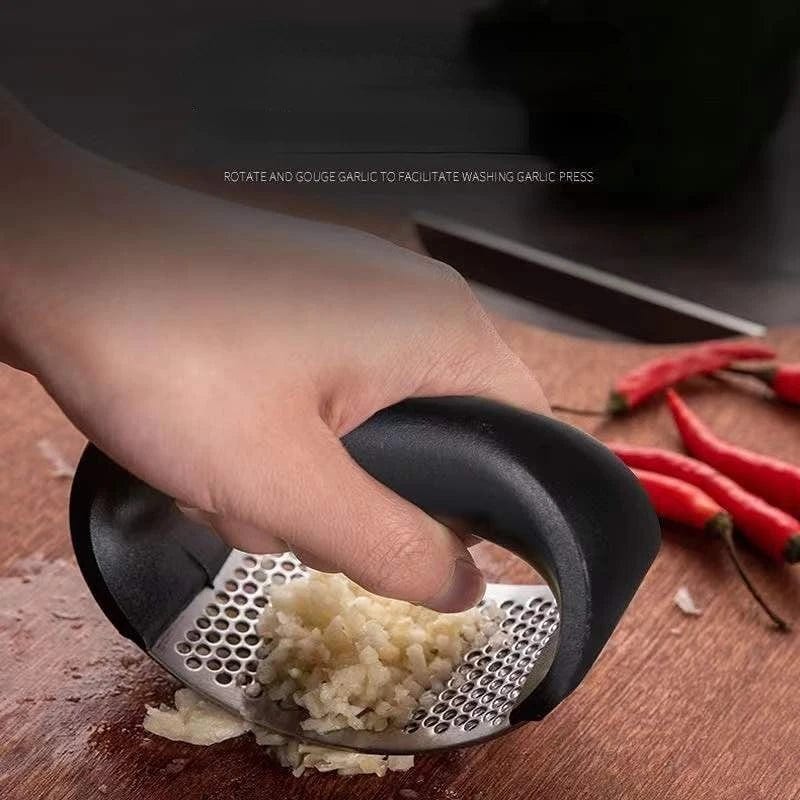 Stainless steel garlic press by Showlu Fashion Store, manual garlic mincer and crusher tool for kitchen use.
