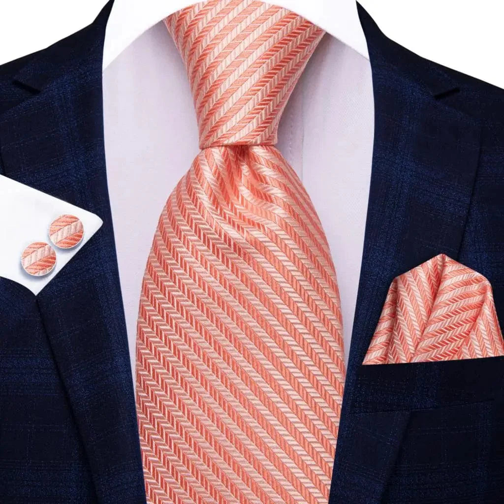 Orange and white striped silk necktie set with matching pocket square and cufflinks, stylish men's wedding accessory.