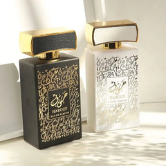 Two rectangular Harouf eau de parfum bottles, one black and one white, with gold calligraphy.