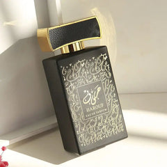A black rectangular perfume bottle with gold Arabic calligraphy and a textured black cap.