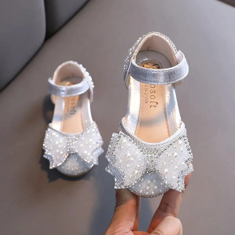 Girls' flat leather princess sandals with sequins, bow detail, and rhinestones, perfect for summer parties and special occasions.