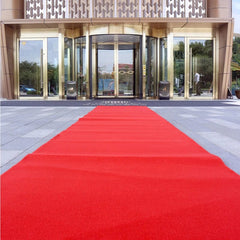 A long red non-woven carpet runner laid out leading to a hotel entrance.