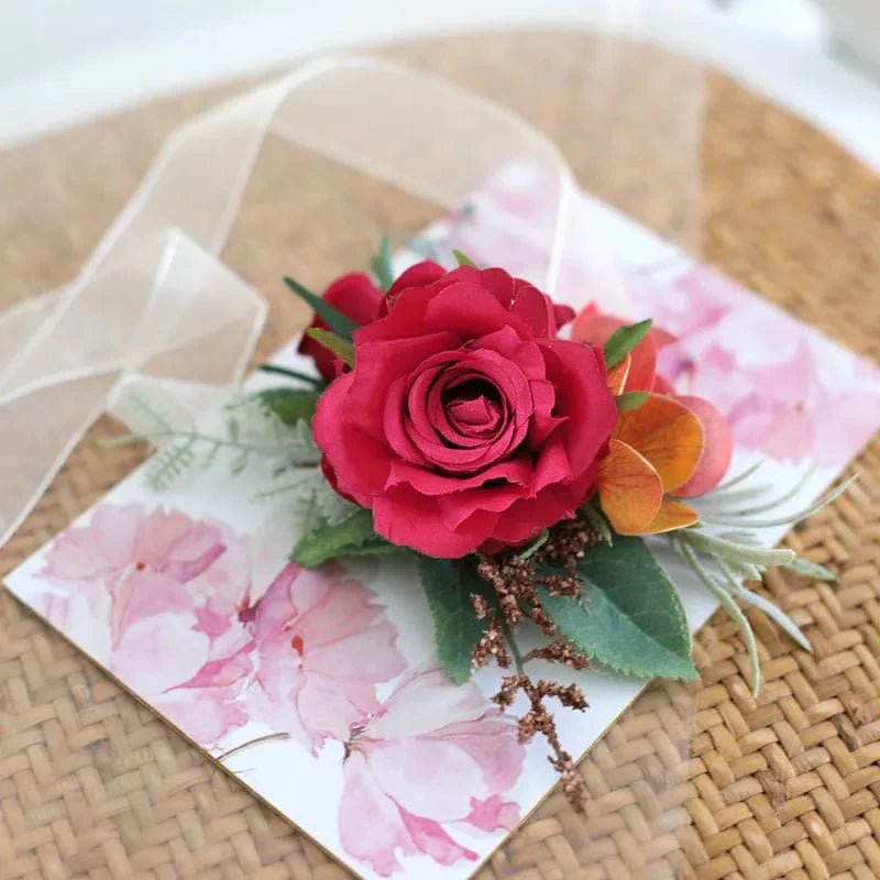 Artificial white boutonniere and wrist corsage with red roses for wedding, showing Showlu Fashion's floral wedding accessories.