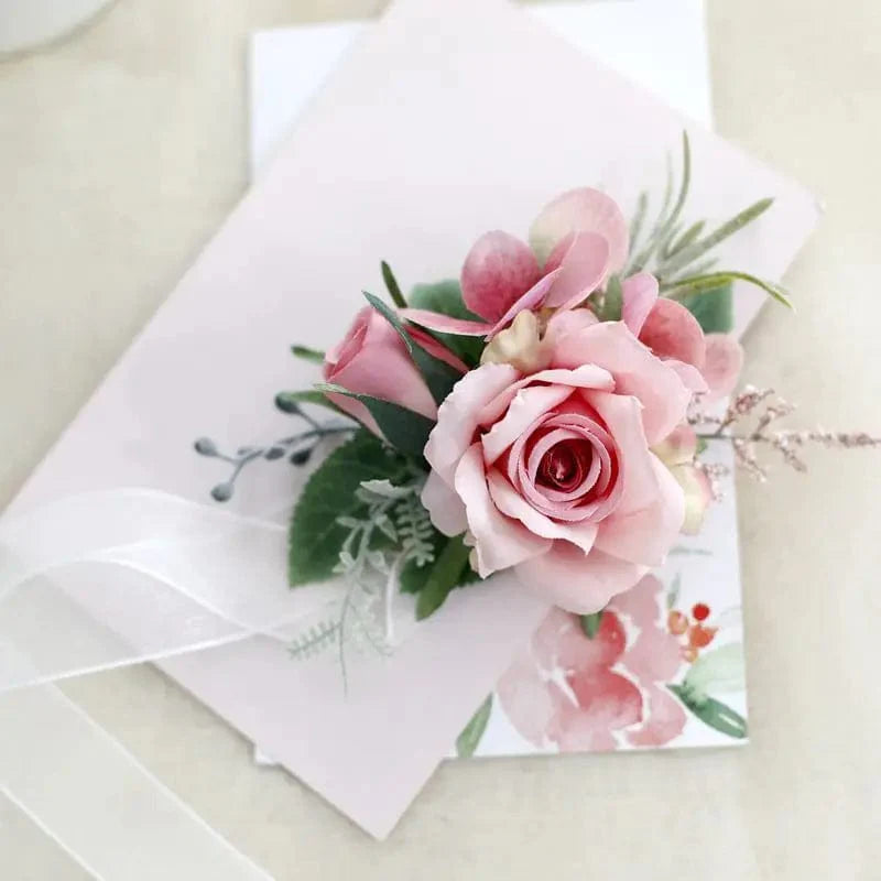 Artificial white silk rose boutonniere and wrist corsage with red rose accents, suitable for wedding bridesmaids, grooms, and guests.